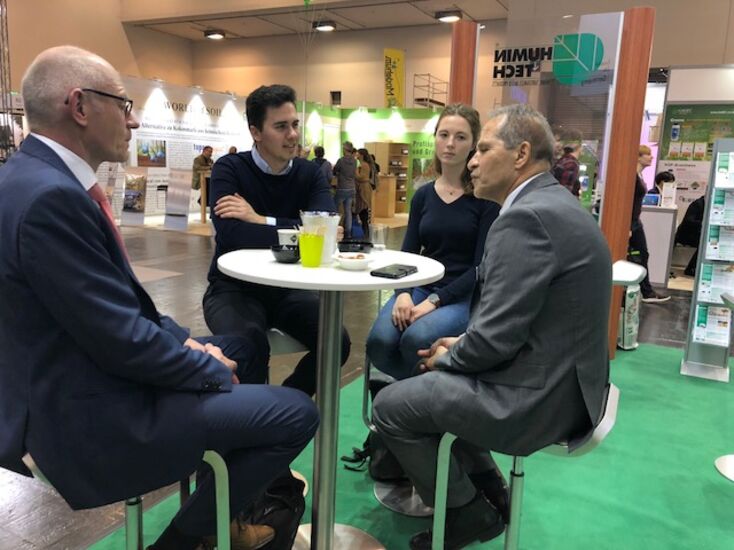 Foto vom Humintech Messestand, vier Personen in einem Gespräch